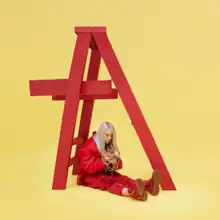 Eilish is seen sitting below a red ladder, holding jewelry that is around her neck.