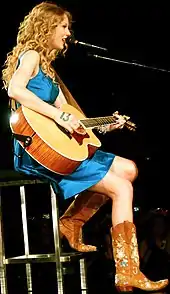 Taylor Swift in a blue dress and cowboy boots, with a guitar, performing at Boston, U.S., in May 2010