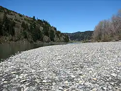 A big patch of bright-colored stones beside the shallow-looking river