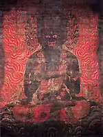 Frontal view of a fierce looking black deity surrounded by flames.