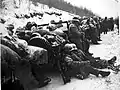 A convoy in the ．snow with men resting on the vehicles