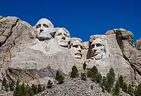 Heads of four presidents carved into the mountain with blue sky