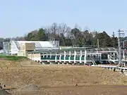 車站全景。屋頂上有風力發電機。前方空地在2012年新建公寓（2007年2月21日）