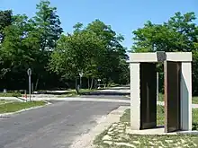 Tree-lined road with gates and a guardhouse