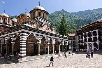 Church with frescos, courtyard with tourists in front