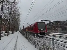 雪中的哥本哈根市郊铁路E线列车。这时已更新至第四代哥本哈根市郊铁路列车，该车的具体型号为丹麦国铁SA型电力动车组。拍摄于2016年时的东铁街。