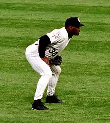 Baseball player in a black and white jersey, holding his cap