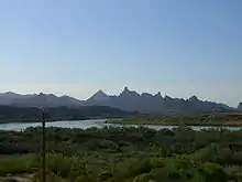 一條寬闊的河川流經森林區，背景有著鋸齒形狀的山脈。