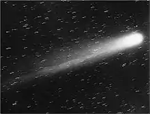 Black-and-white picture of the comet, its nucleus brilliant white, and its tail very prominent, moving up and to the right