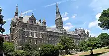 A large Gothic style stone building dominated by a tall clocktower.