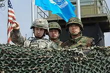 大韓民國陸軍士兵與美軍上尉軍官站在位在板門店的觀察哨（英语：），一同視察朝韓非軍事區的狀況。